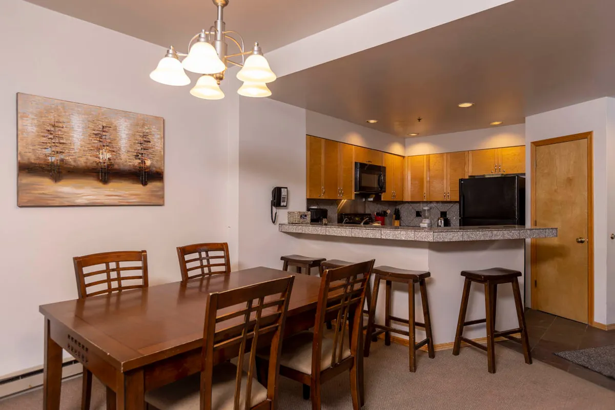 A bright kitchen and dining area featuring a spacious dining table and a well-equipped kitchen with modern appliances and ample counter space. Artwork and thoughtful decor enhance the warm, welcoming atmosphere, inviting guests to cook, gather, and create lasting memories.