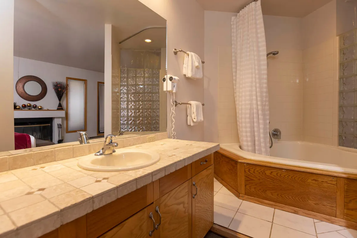 A serene bathroom with a spacious sink area, inviting bathtub, fresh towels, and a large mirror, all set in a calming, light-filled space ideal for relaxation and self-care.